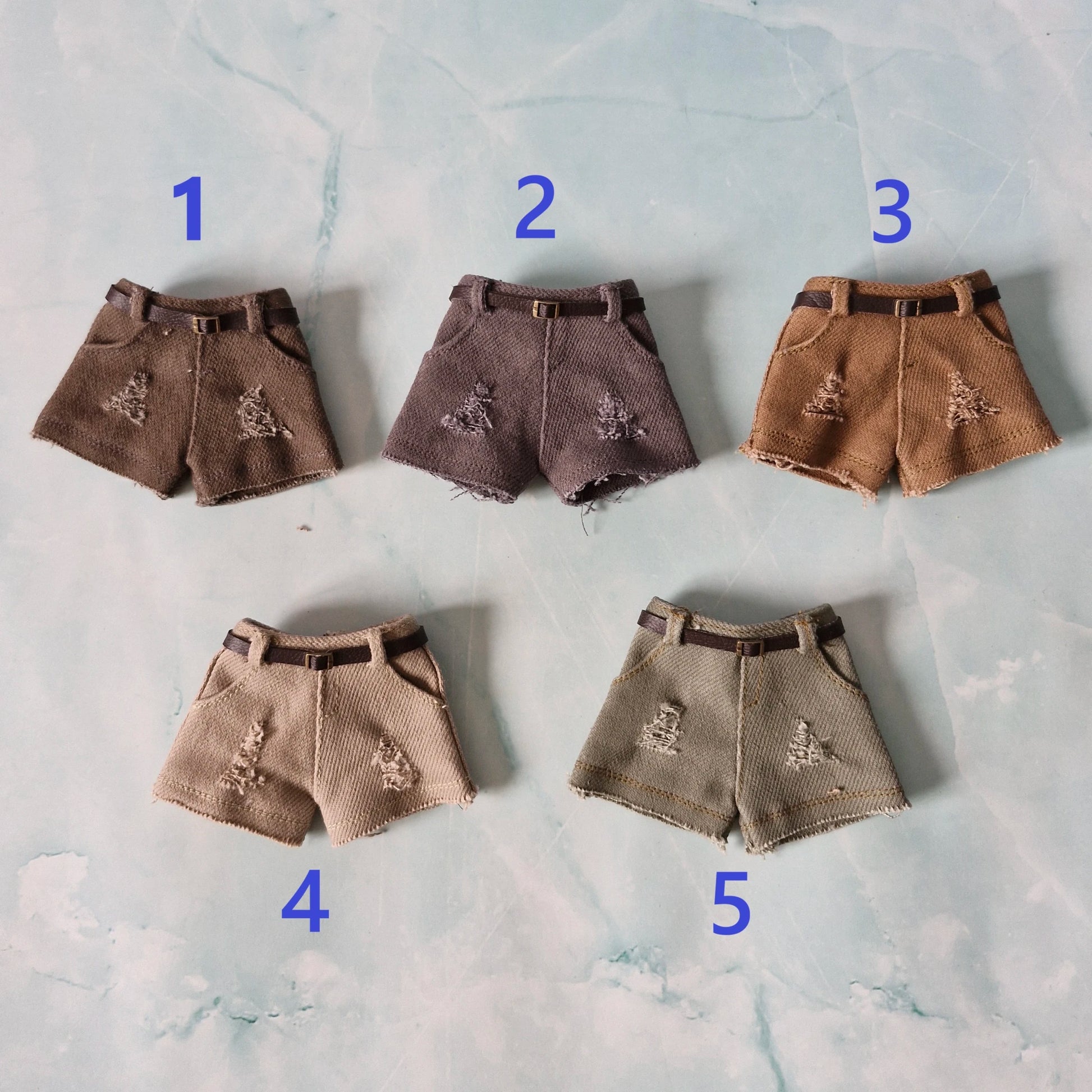 Five pairs of brown shorts with decorative elements on a textured surface