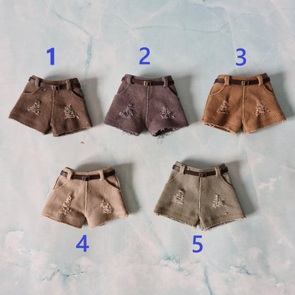 Five pairs of brown shorts with decorative elements on a textured surface