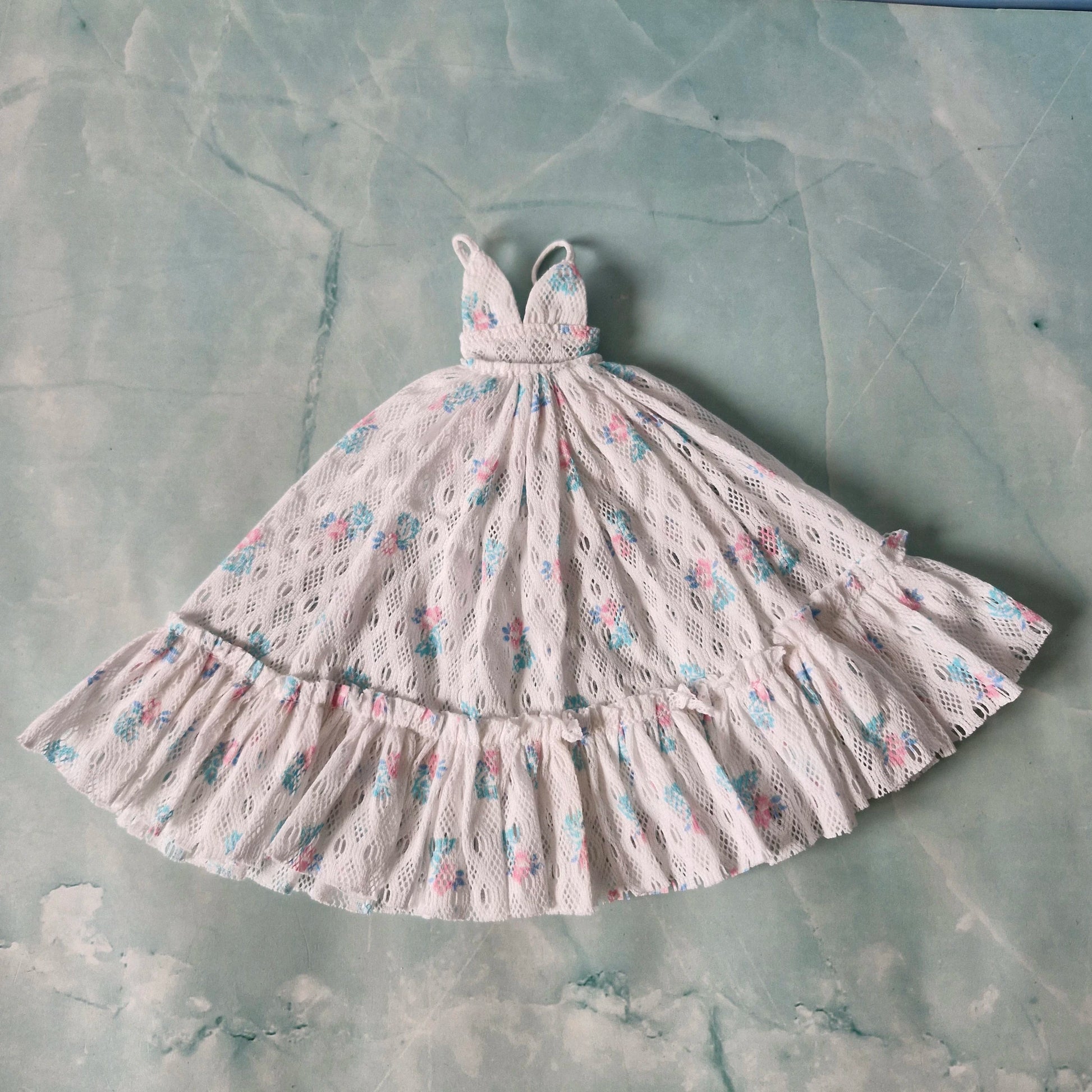 Flat lay of white lace Barbie maxi dress with floral patterns