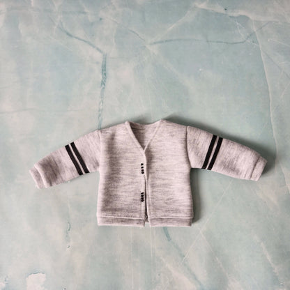 Baby cardigan with striped sleeves on a textured light blue background