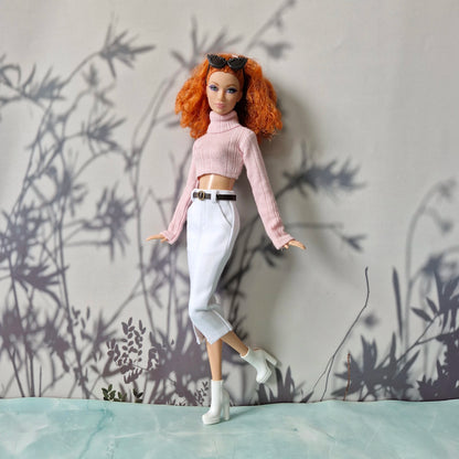 Doll with red hair and pink sweater against a wall with plant shadows