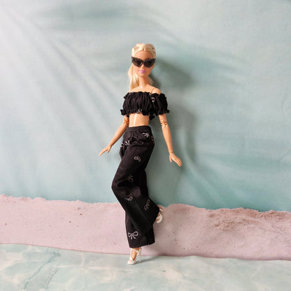 Barbie doll in black outfit with sunglasses on a textured surface