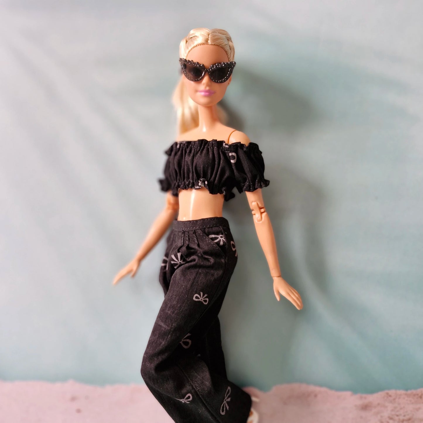 Barbie doll wearing a black outfit with sunglasses on a gray background