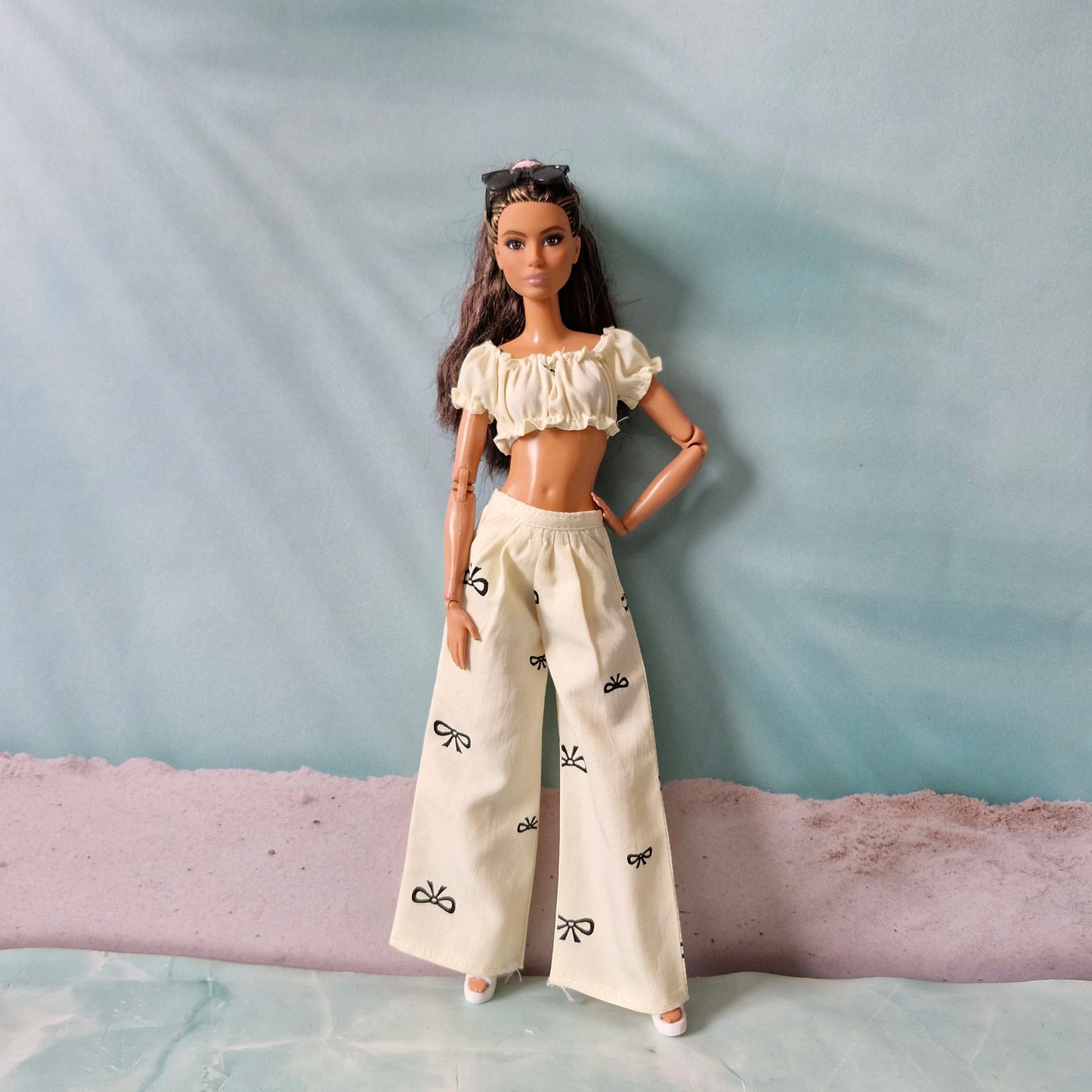 Barbie doll wearing a white outfit with black patterns on a textured surface