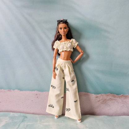 Barbie doll wearing a white outfit with black patterns on a textured surface