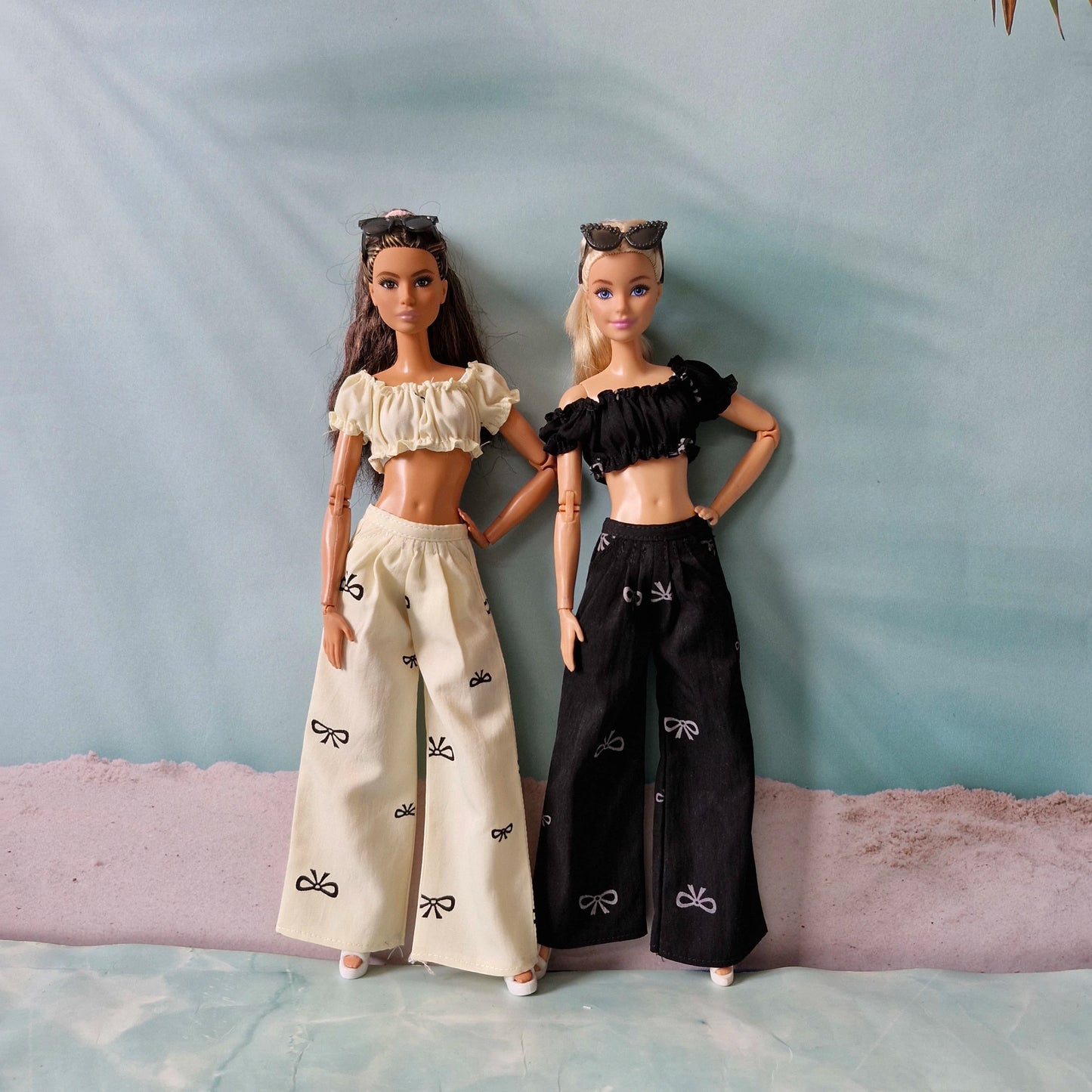 Two dolls wearing matching outfits with a plain background