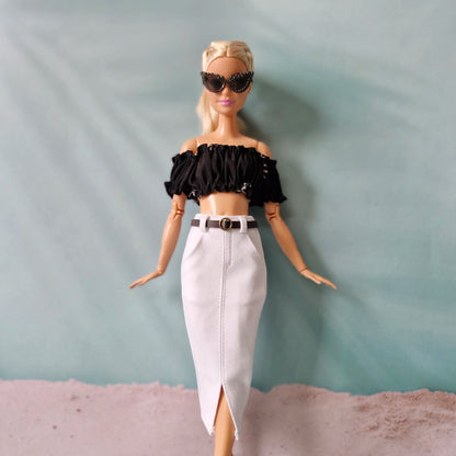 Barbie doll wearing a black top and white skirt against a plain background