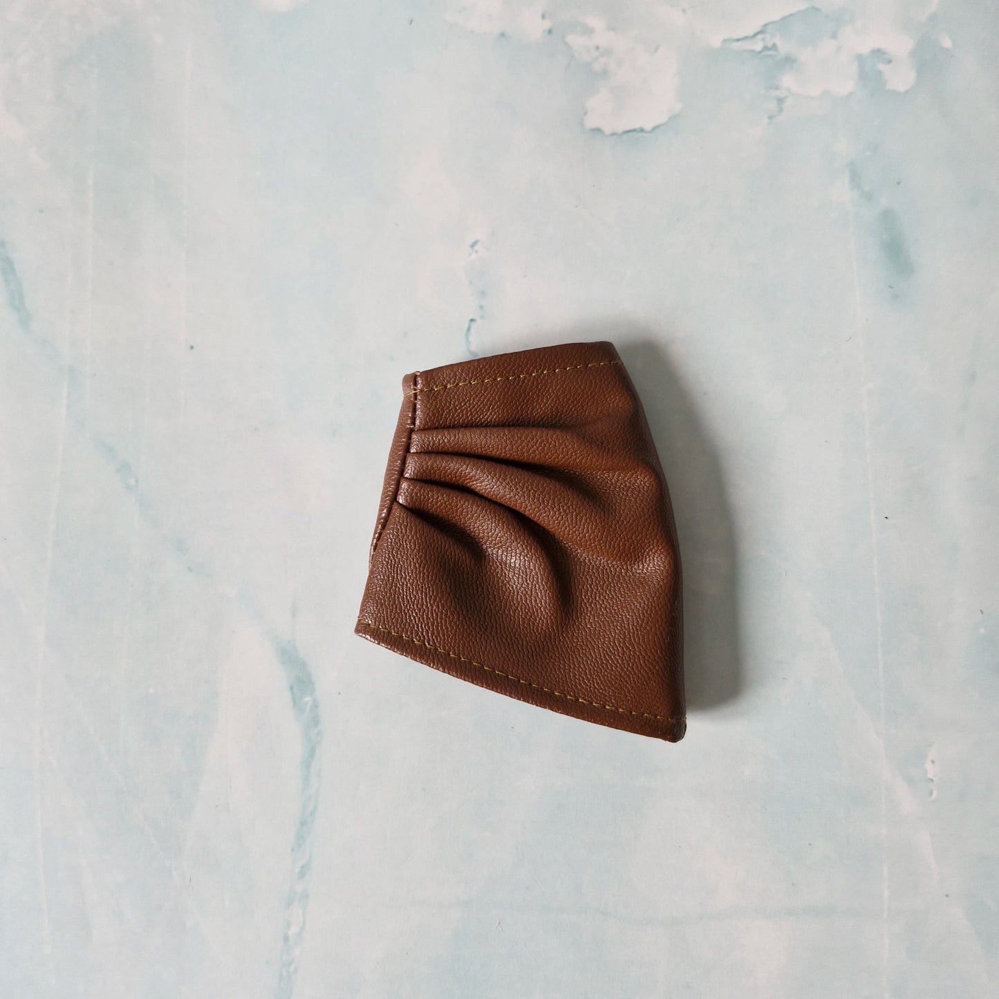 Brown leather wallet on a light blue marble surface