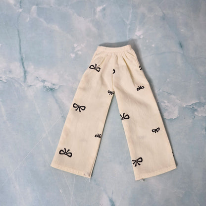 Beige pants with black bow patterns on a textured light blue background