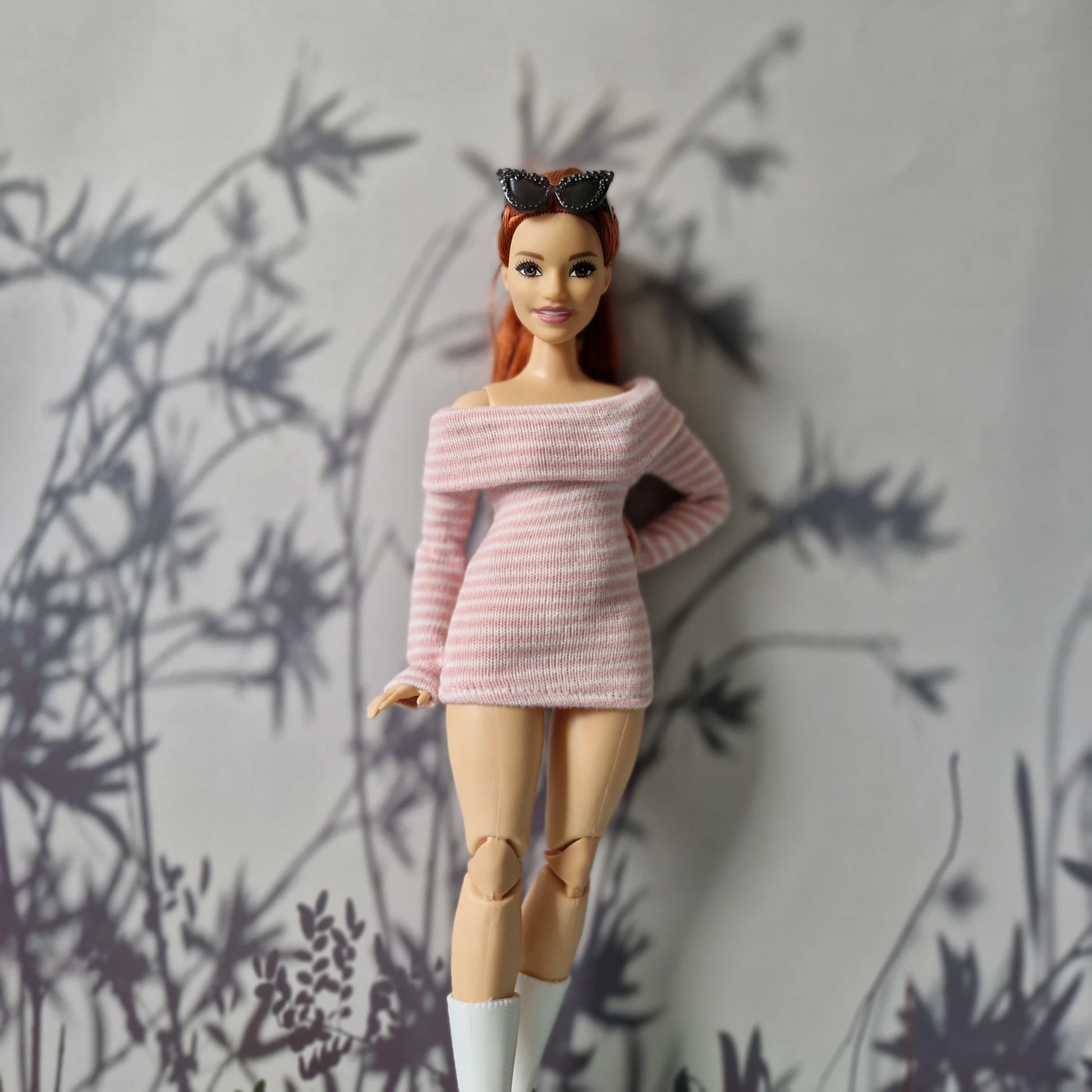 Barbie doll wearing a pink sweater with a heart design against a gray background