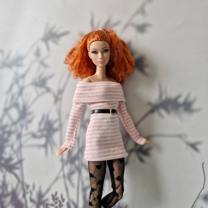 Barbie doll wearing a pink off-shoulder dress with a black belt against a neutral background