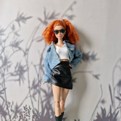 Barbie doll styled with denim jacket over white crop top and black leather skirt

