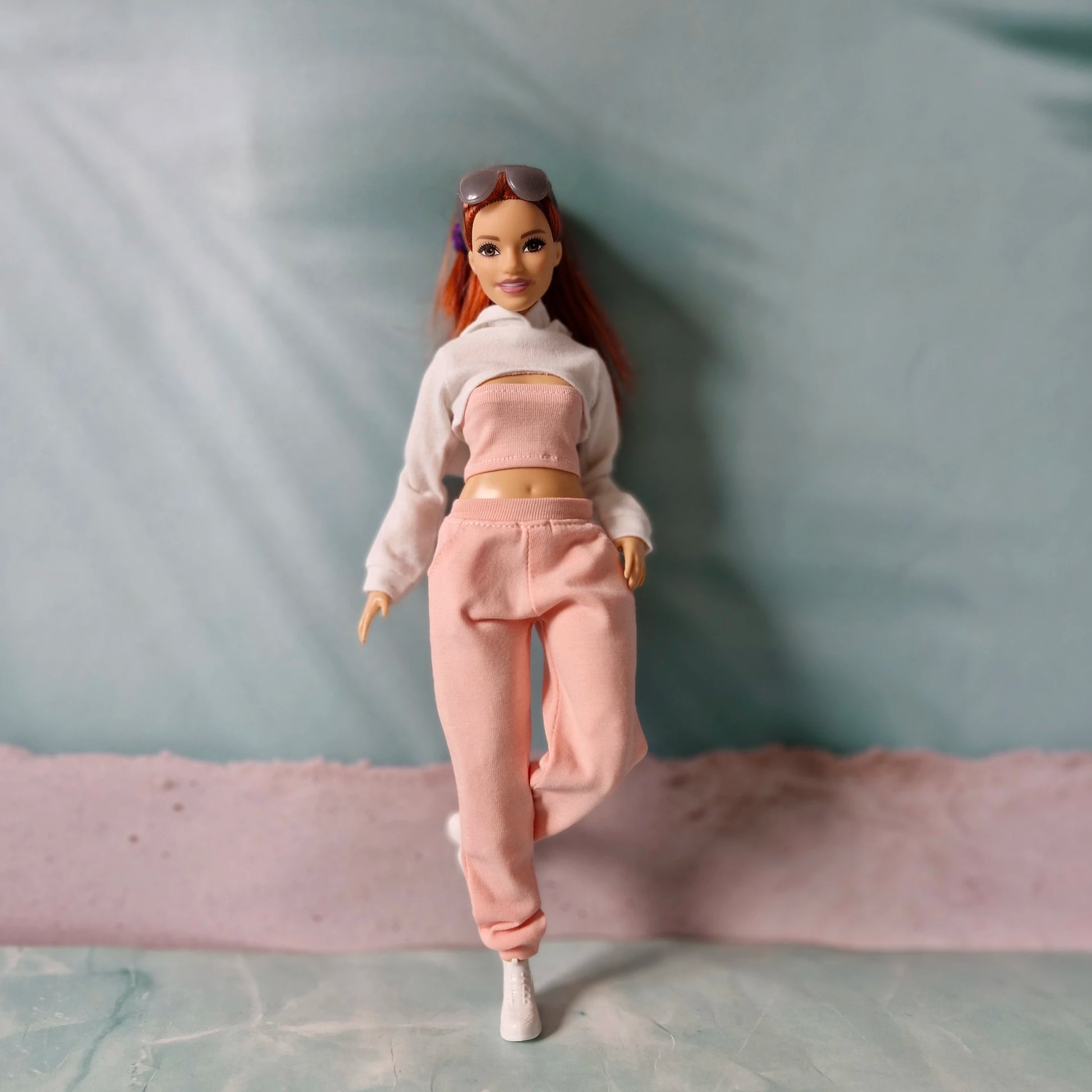 Barbie doll in white cropped hoodie and pink sweatpants walking forward playfully.

