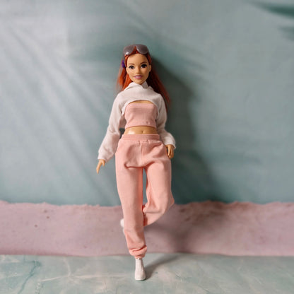 Barbie doll in white cropped hoodie and pink sweatpants walking forward playfully.
