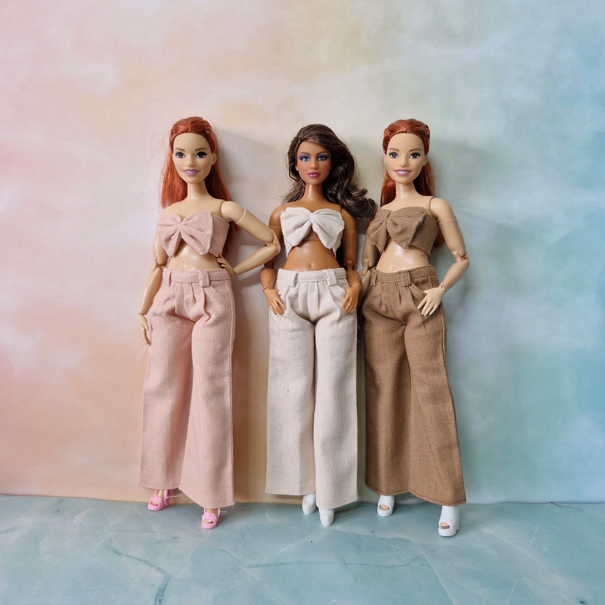 Barbie Curvy doll wearing blush pink bow top and wide-leg pants set, fashion outfit.
