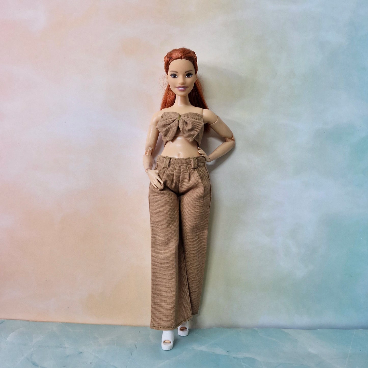 Barbie Curvy doll posing in camel brown bow top with wide-leg pants, neutral tones.

