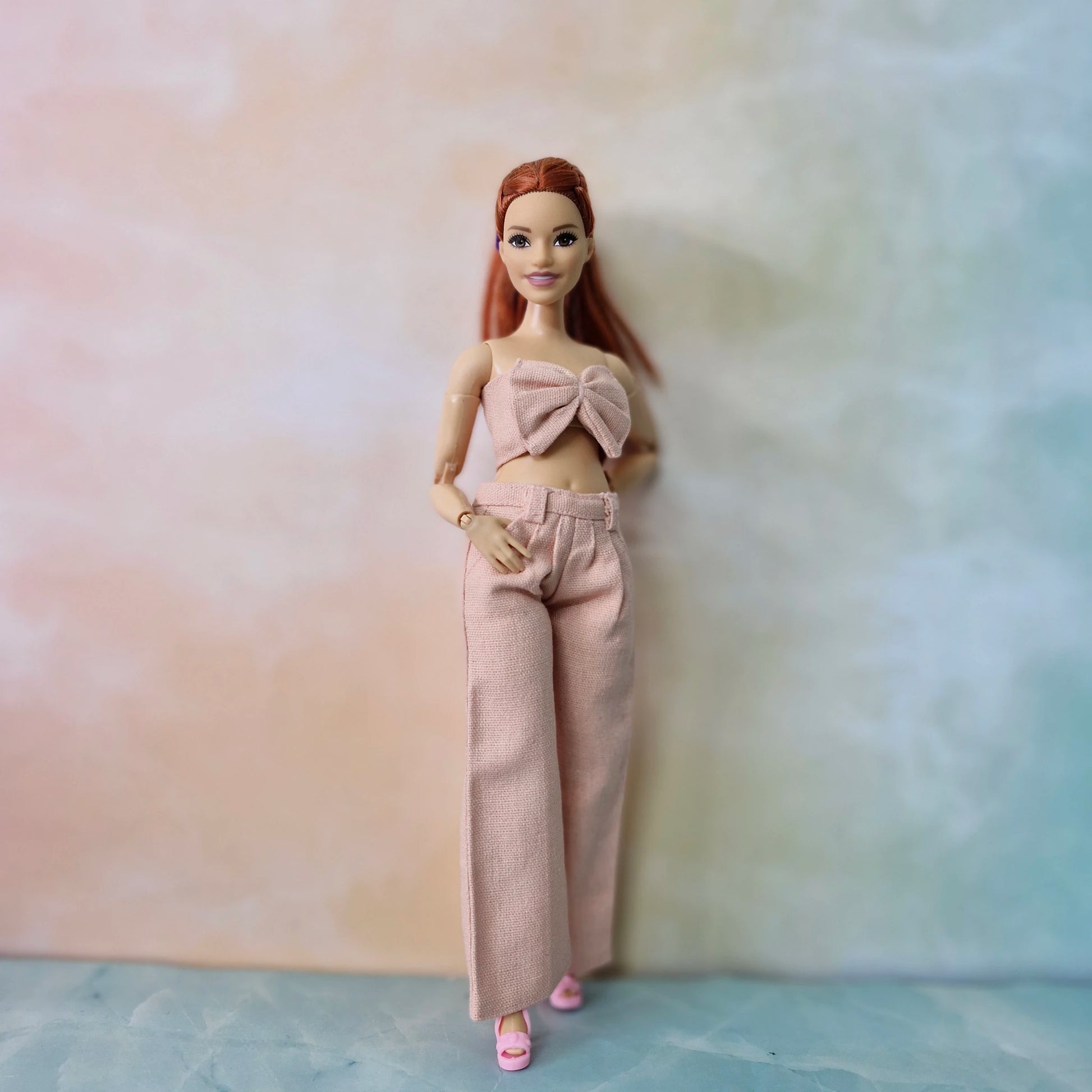Barbie Curvy doll in blush pink bow crop top and wide-leg trousers, pastel fashion set.
