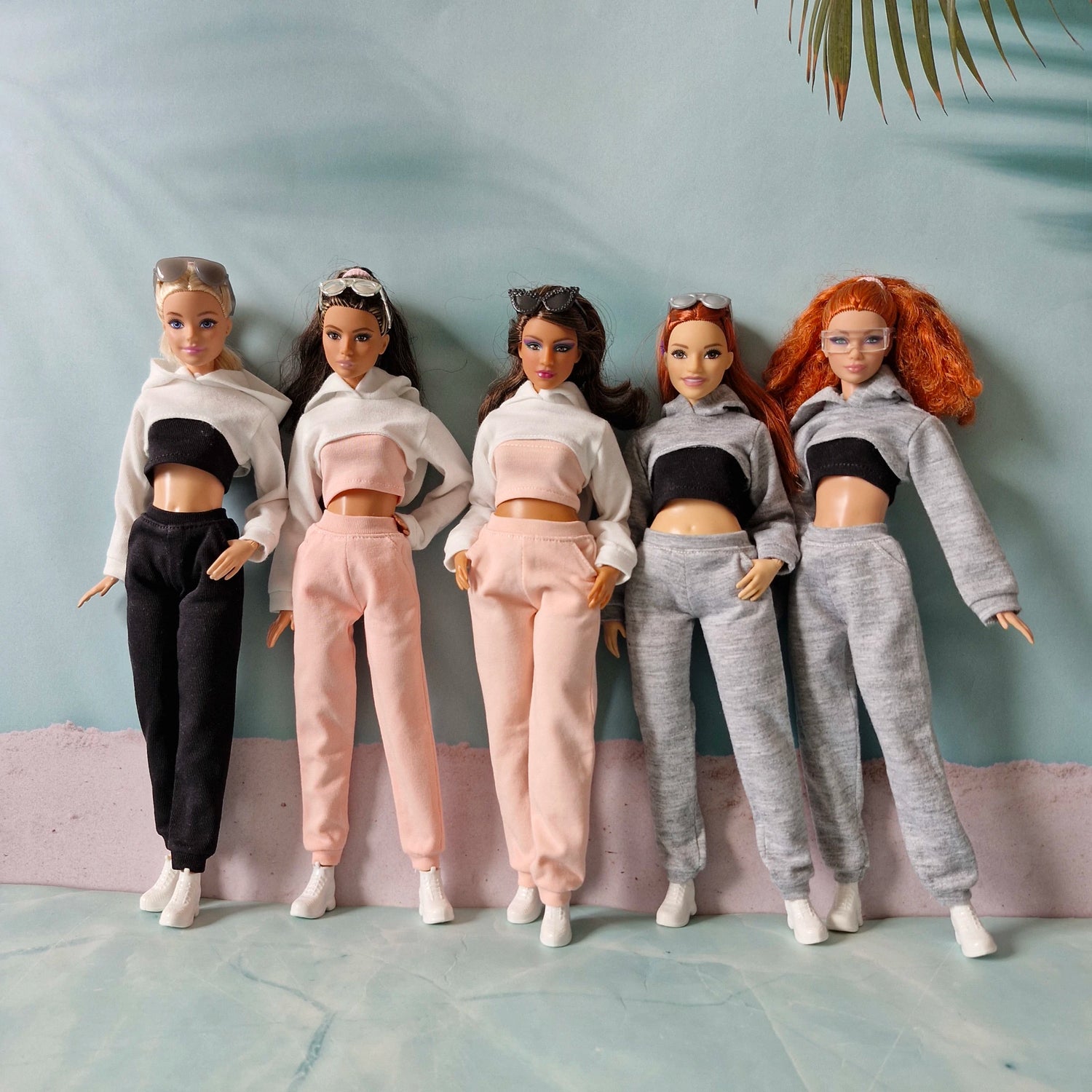 Group of five Barbie dolls in diverse sizes wearing black pink and grey streetwear collections