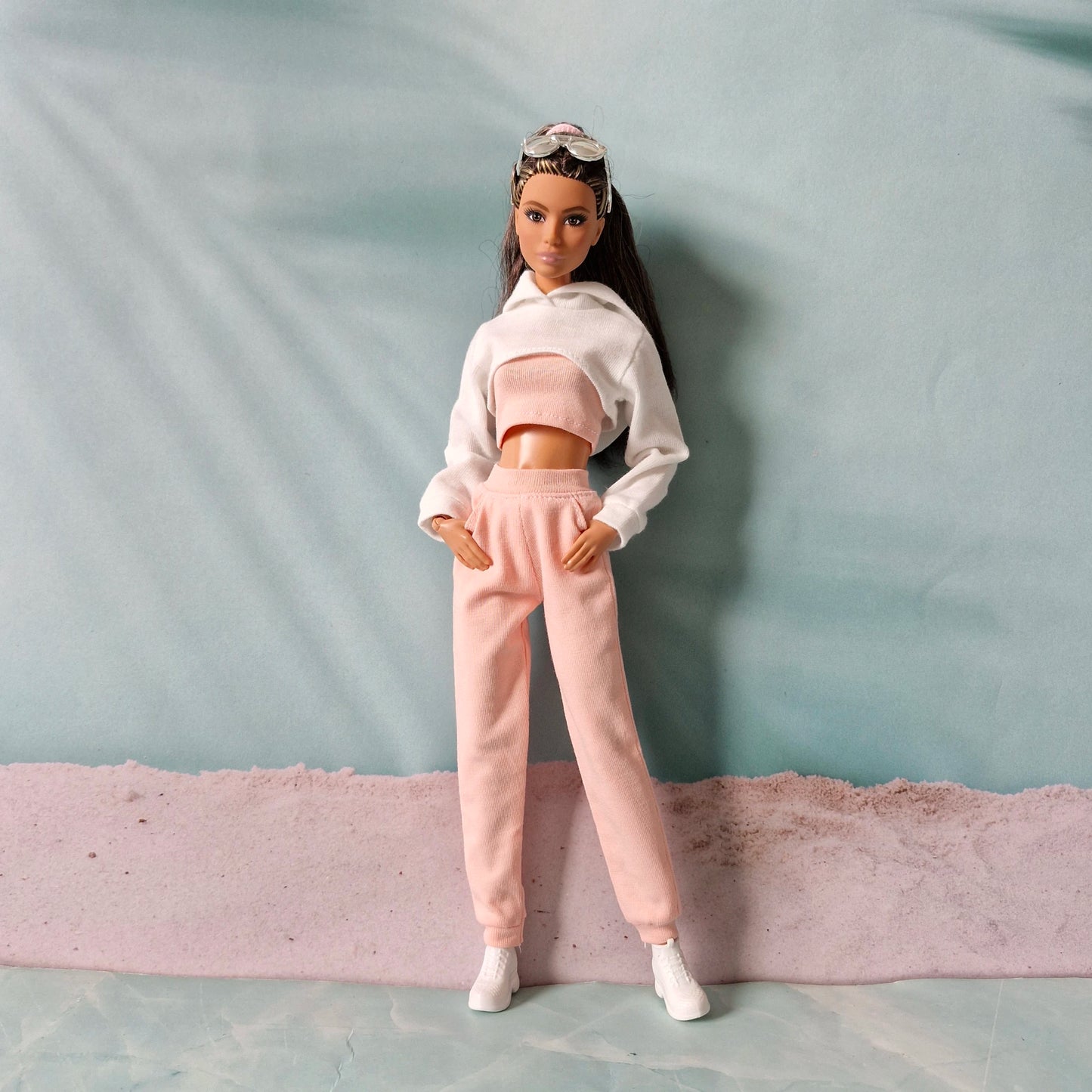 Brunette Barbie doll posing in pink joggers and white super cropped hoodie outfit