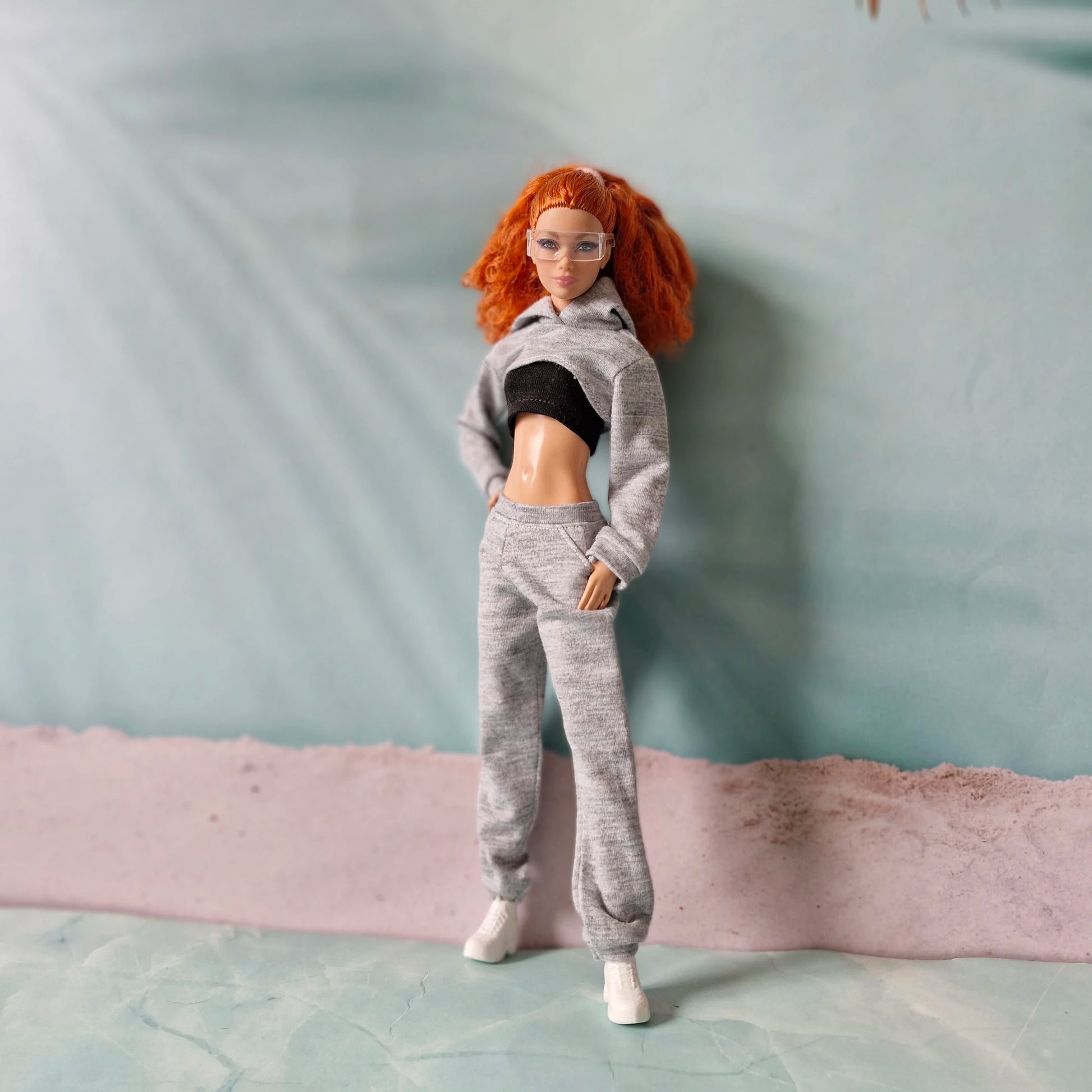 Curly redhead fashion doll modeling grey athleisure outfit with cropped hoodie and joggers