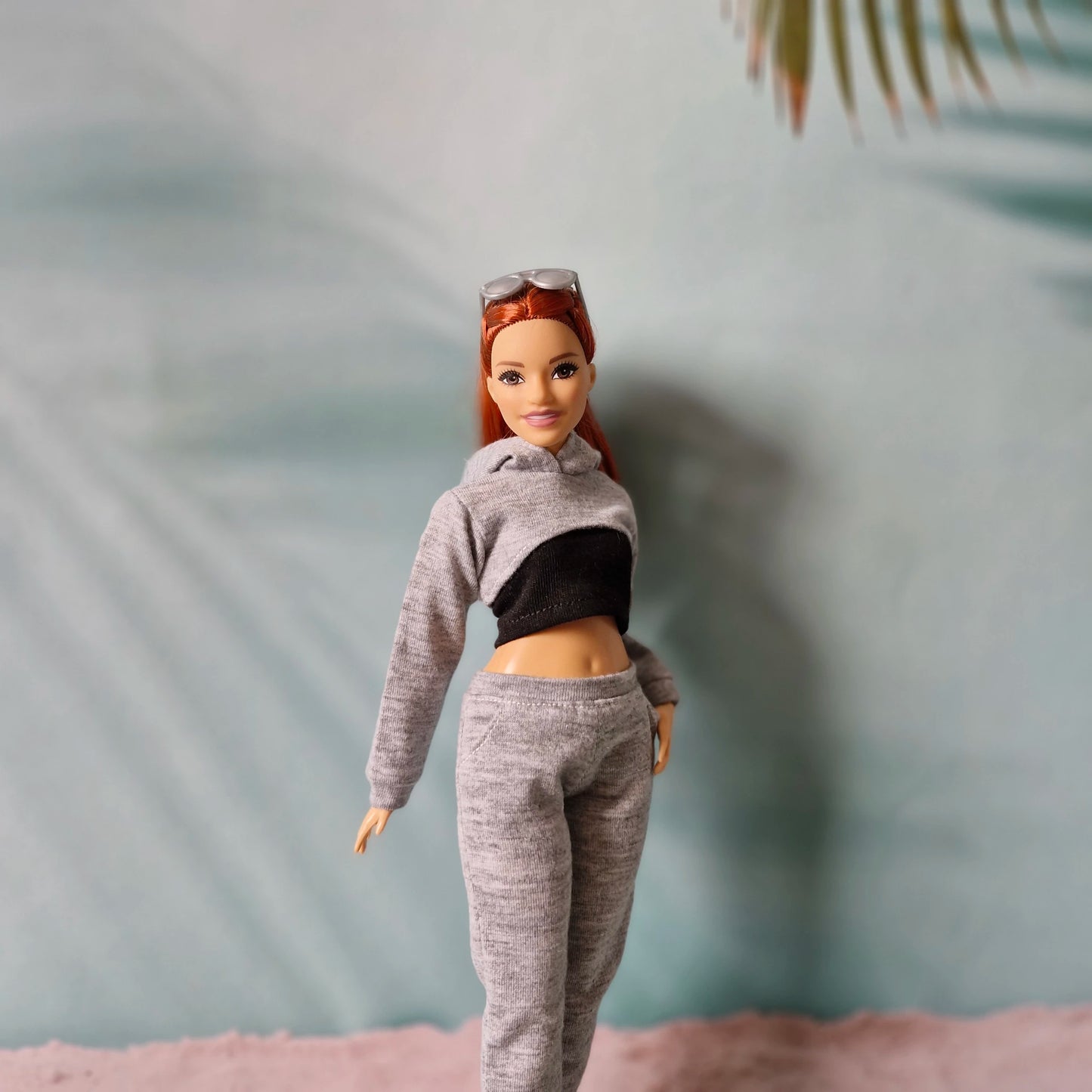 Close up of Barbie doll wearing grey cropped hoodie with black tube top underneath