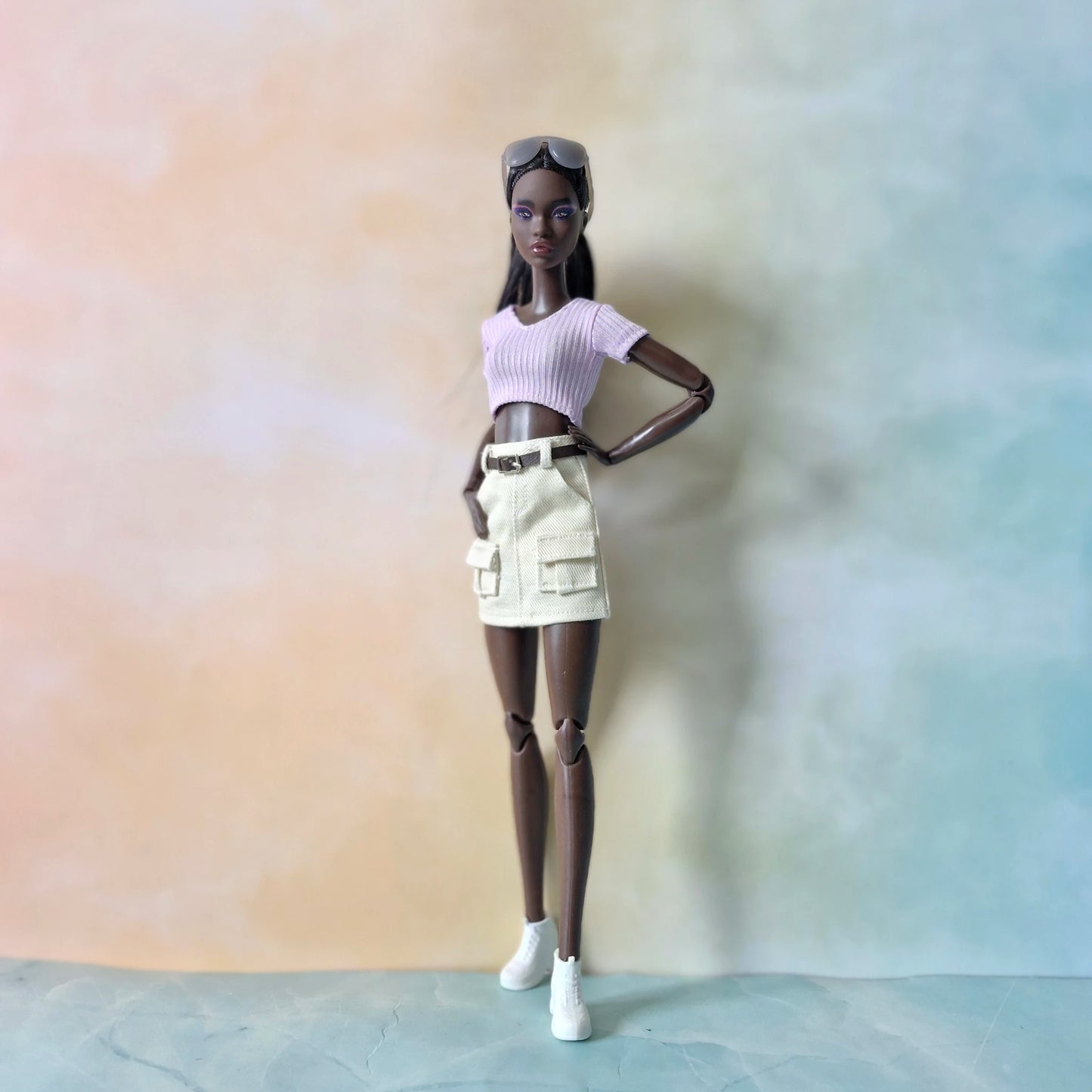 Model doll posing in trendy streetwear outfit with pastel purple top and cargo skirt