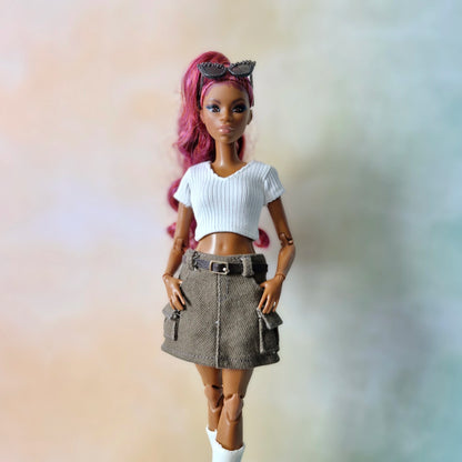 Close up of doll fashion featuring white v-neck crop top and brown mini skirt with belt