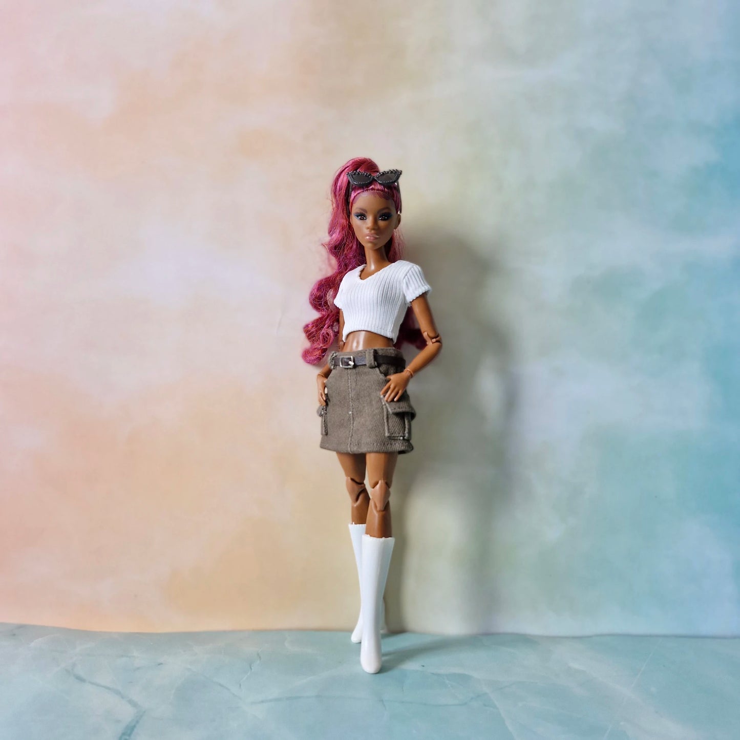 Fashion doll with pink hair wearing white ribbed top and olive brown corduroy mini skirt