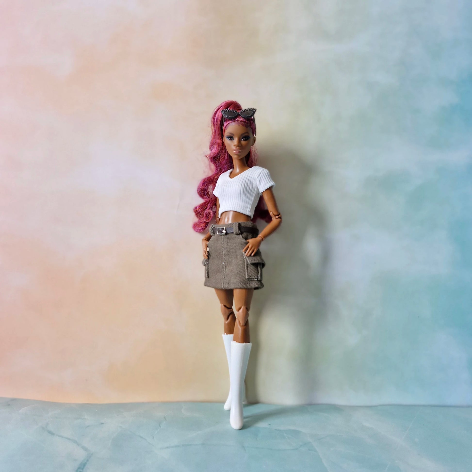 Fashion doll with pink hair wearing white ribbed top and olive brown corduroy mini skirt