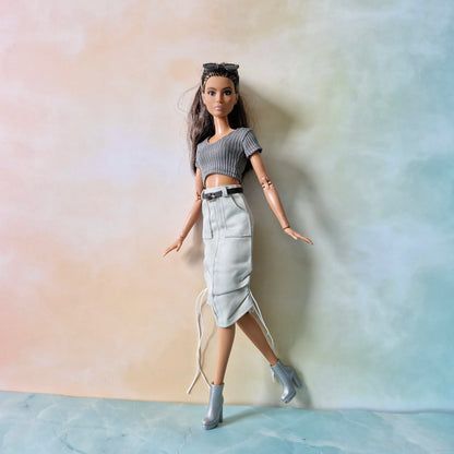 Barbie doll wearing a crop top and skirt against a gradient background