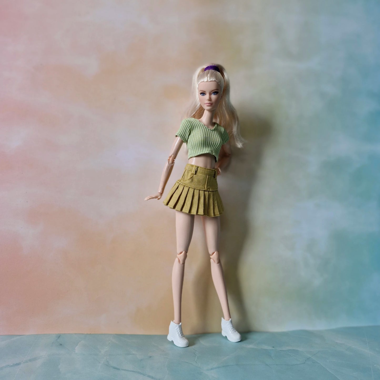 Barbie doll in a green top and skirt against a gradient background
