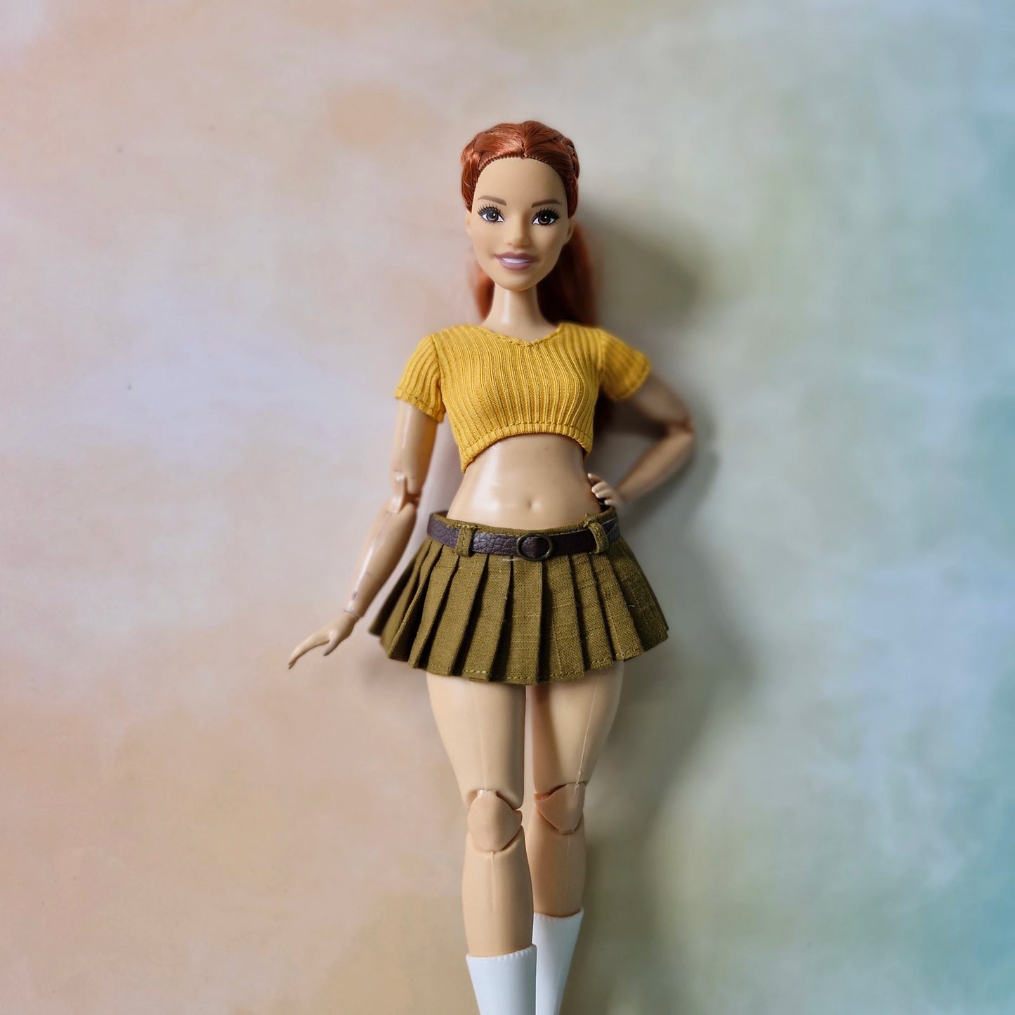 Redhead curvy doll posing in mustard yellow knit top and pleated tennis skirt