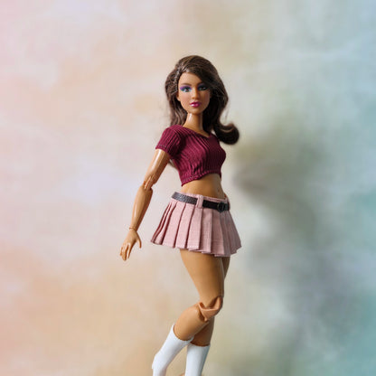 Brunette curvy doll wearing burgundy ribbed top and dusty pink pleated skirt