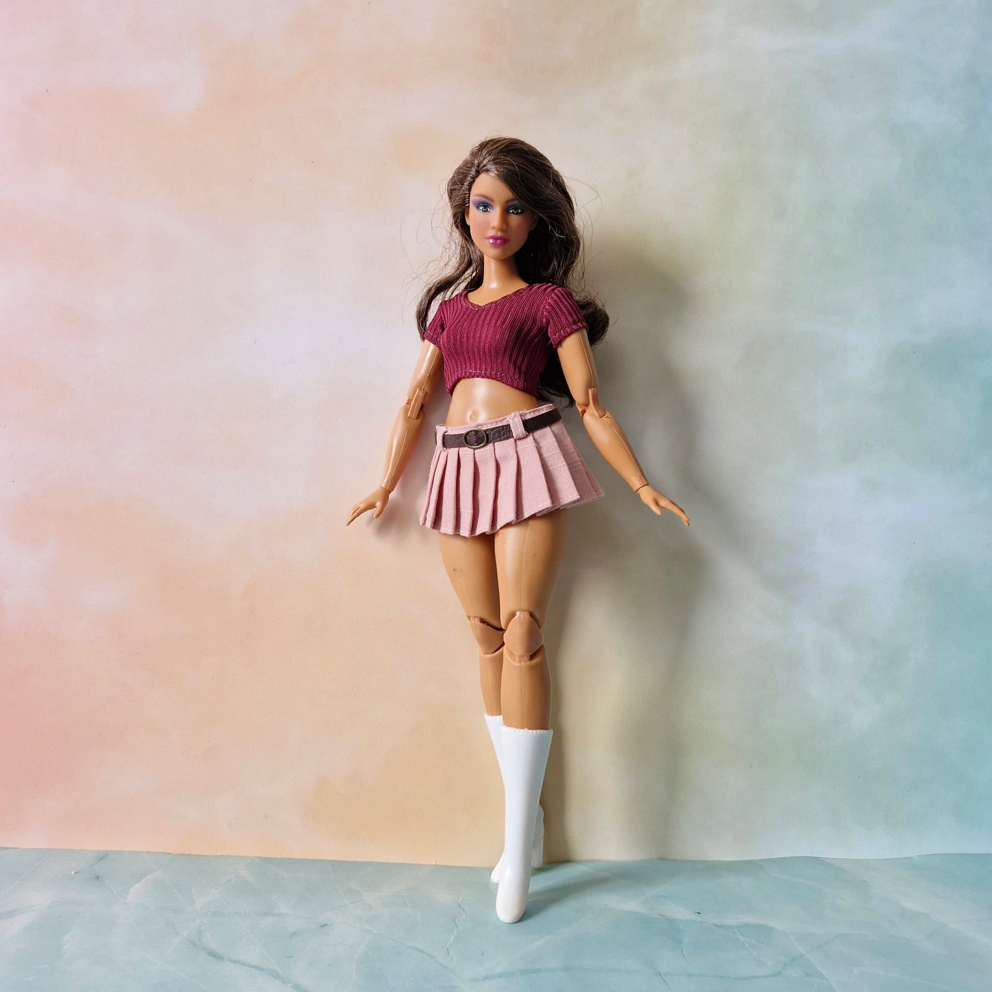 Full body shot of curvy fashion doll in pink skirt and maroon crop top with white socks