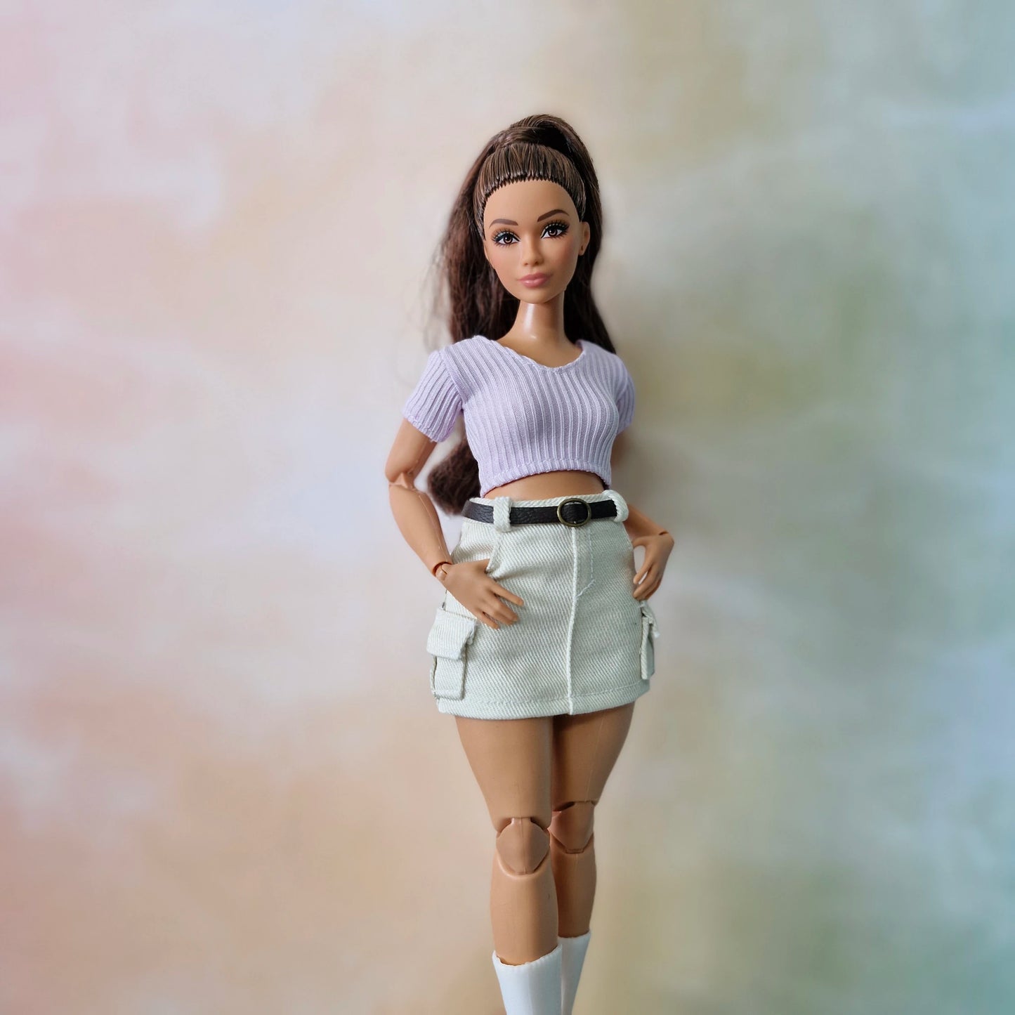 Barbie doll wearing a purple top and white skirt against a blurred background