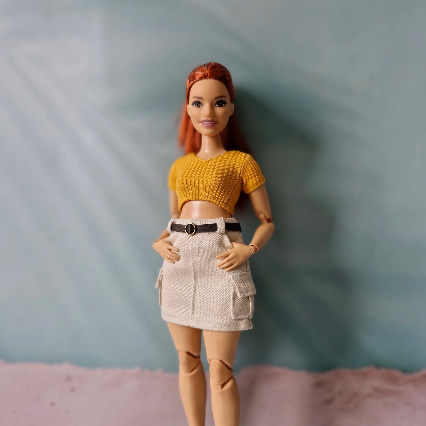Redhead Barbie doll posing with hands in pockets wearing beige cargo skirt and yellow crop top