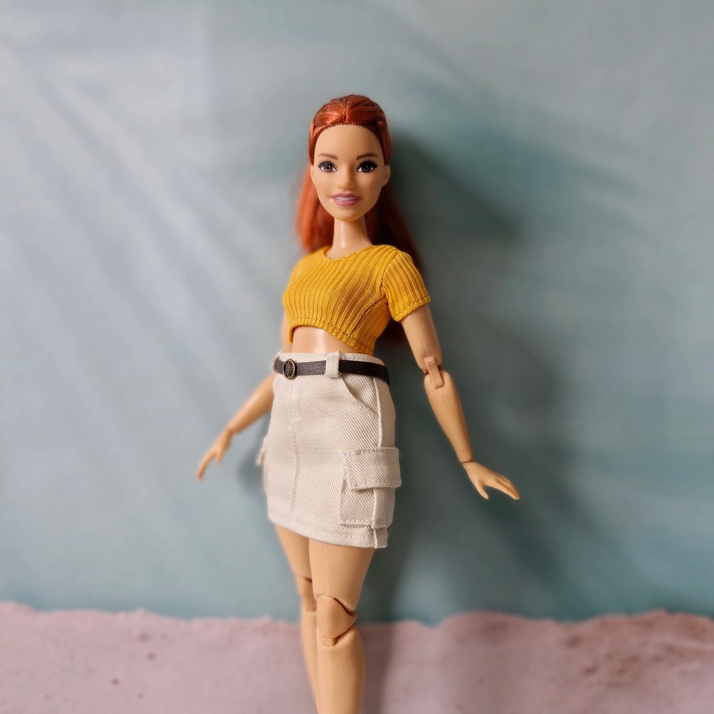 Curvy fashion doll wearing yellow ribbed crop top and beige cargo mini skirt standing pose