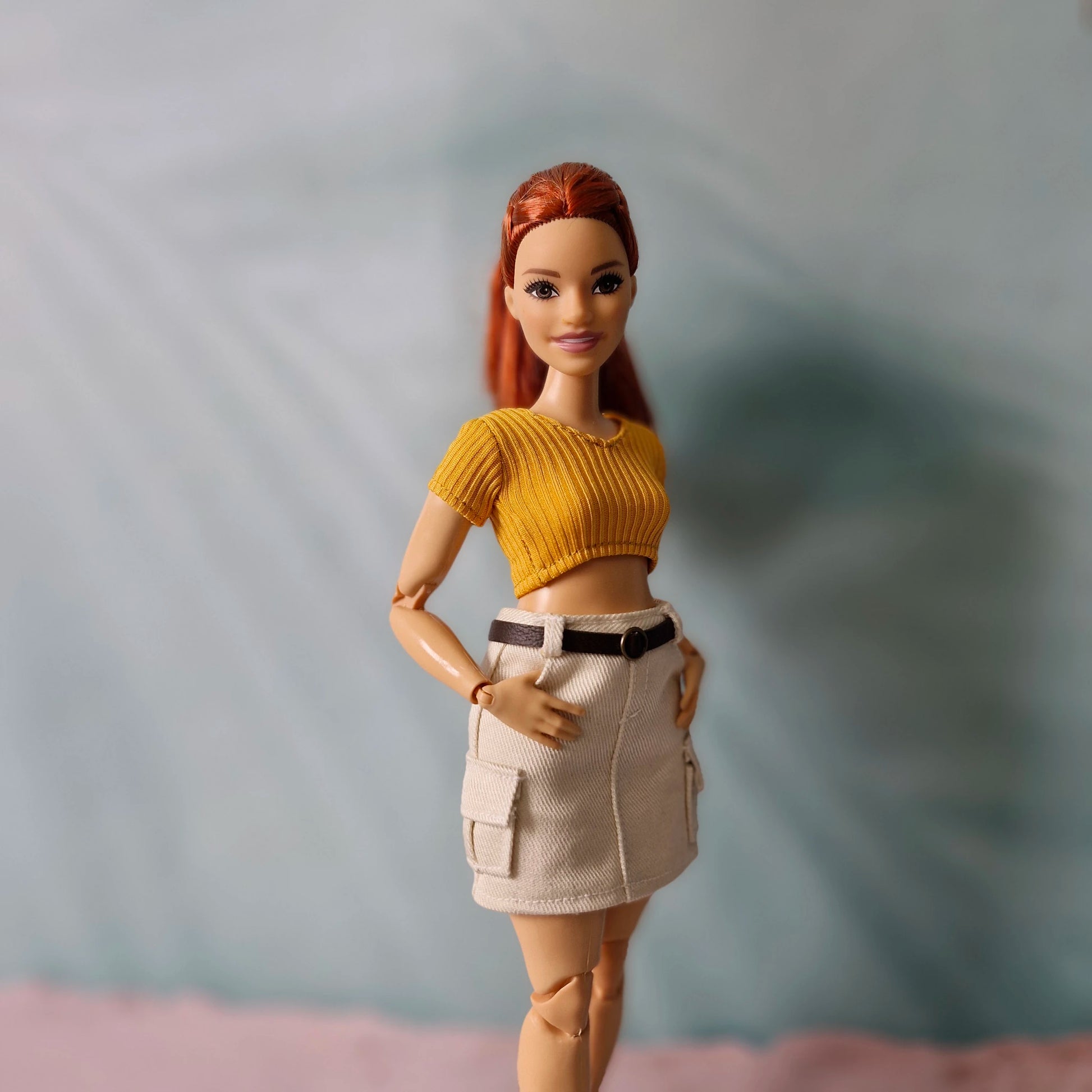 Side view of curvy doll wearing ribbed crop top and cargo skirt with belt detail