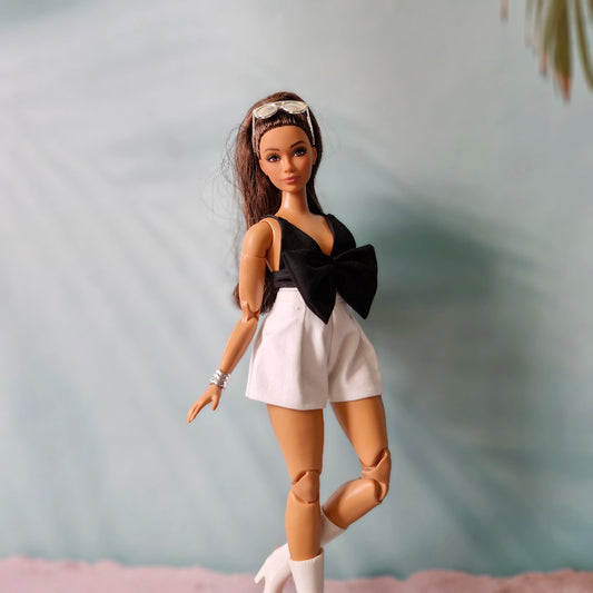 Stylish Curvy Barbie doll posing in a strapless black bow romper