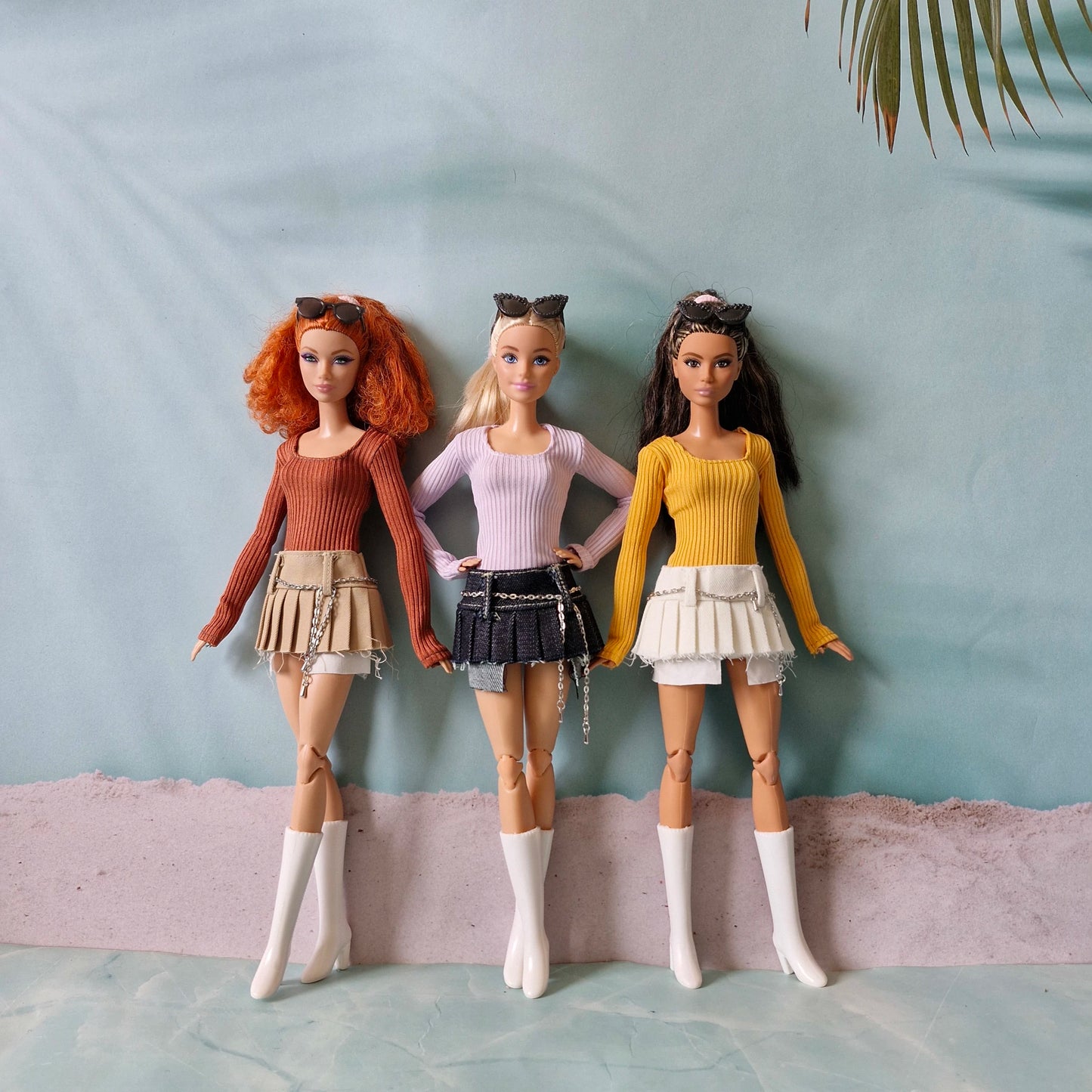 Group of three Barbie dolls wearing mix and match ribbed tops and pleated skirts with chain belts