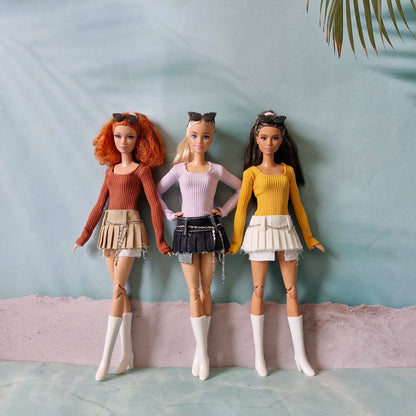 Group of three Barbie dolls wearing mix and match ribbed tops and pleated skirts with chain belts
