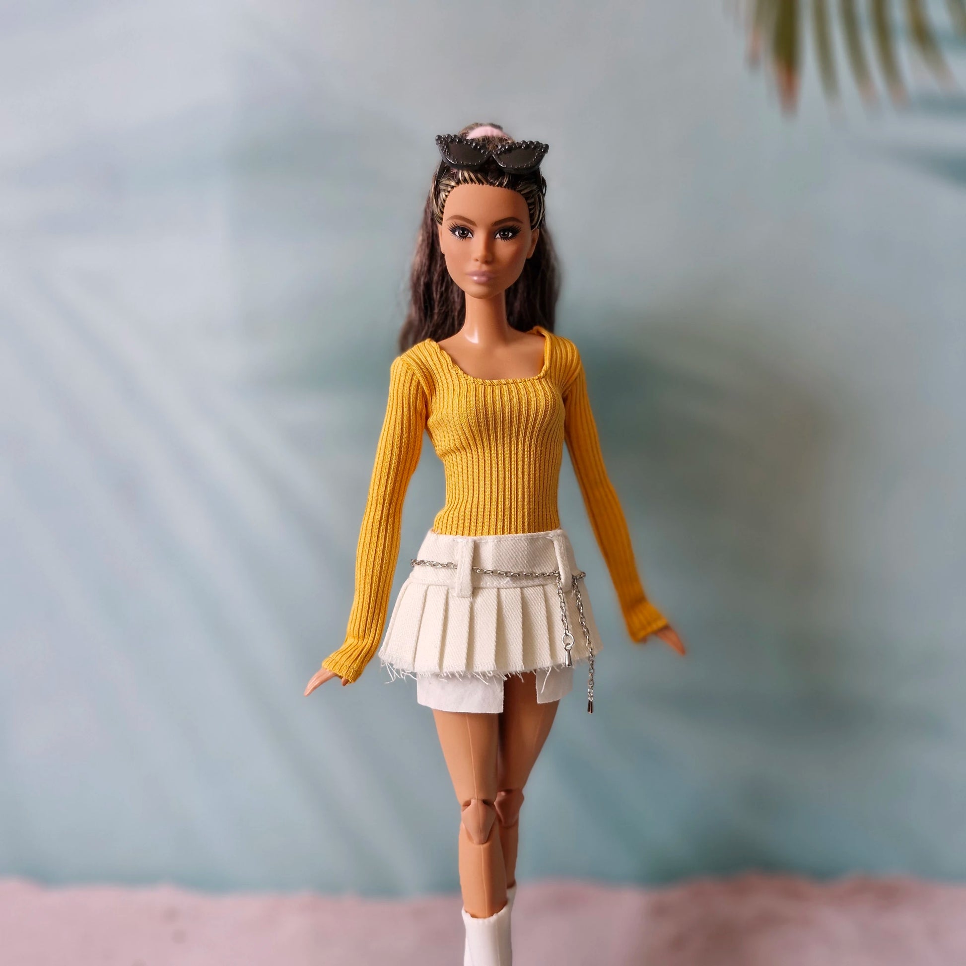 Brunette Barbie doll wearing mustard yellow top and white pleated mini skirt walking pose