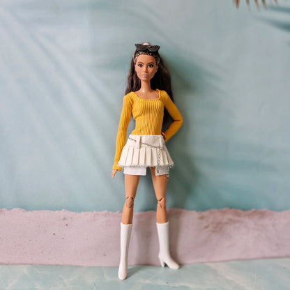 Full body shot of doll wearing yellow ribbed shirt and white denim skirt with chain