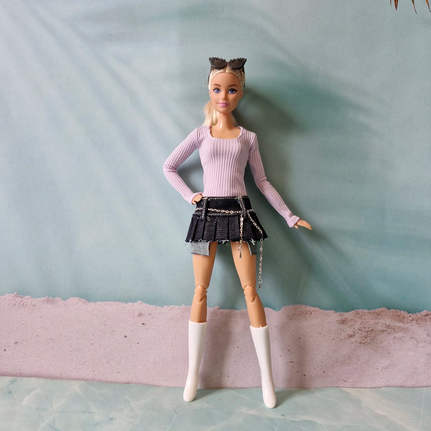 Fashion doll wearing pastel purple top and black mini skirt with silver chain belt detail