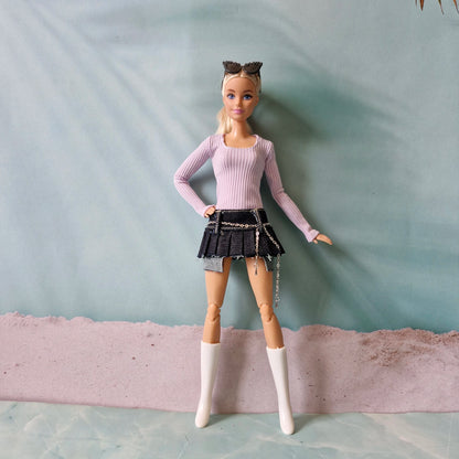 Fashion doll wearing pastel purple top and black mini skirt with silver chain belt detail