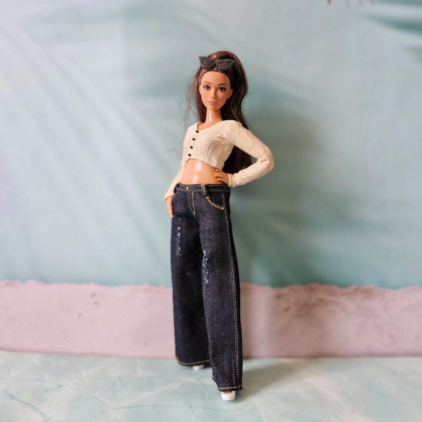 Curvy Barbie doll posing in dark blue distressed wide leg jeans and knit cardigan