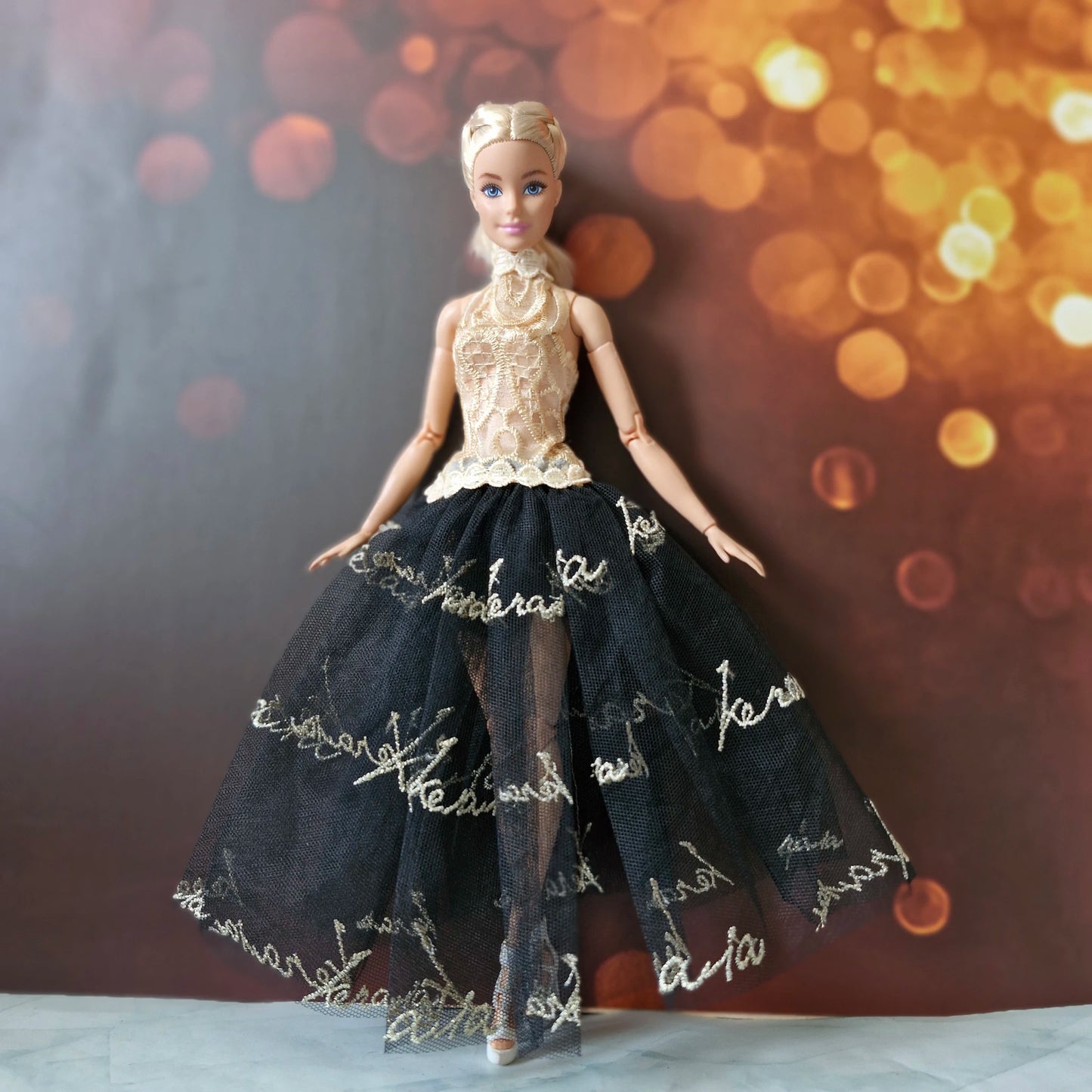 Front view of Barbie wearing a sophisticated gold and black tulle evening gown with sparkling background