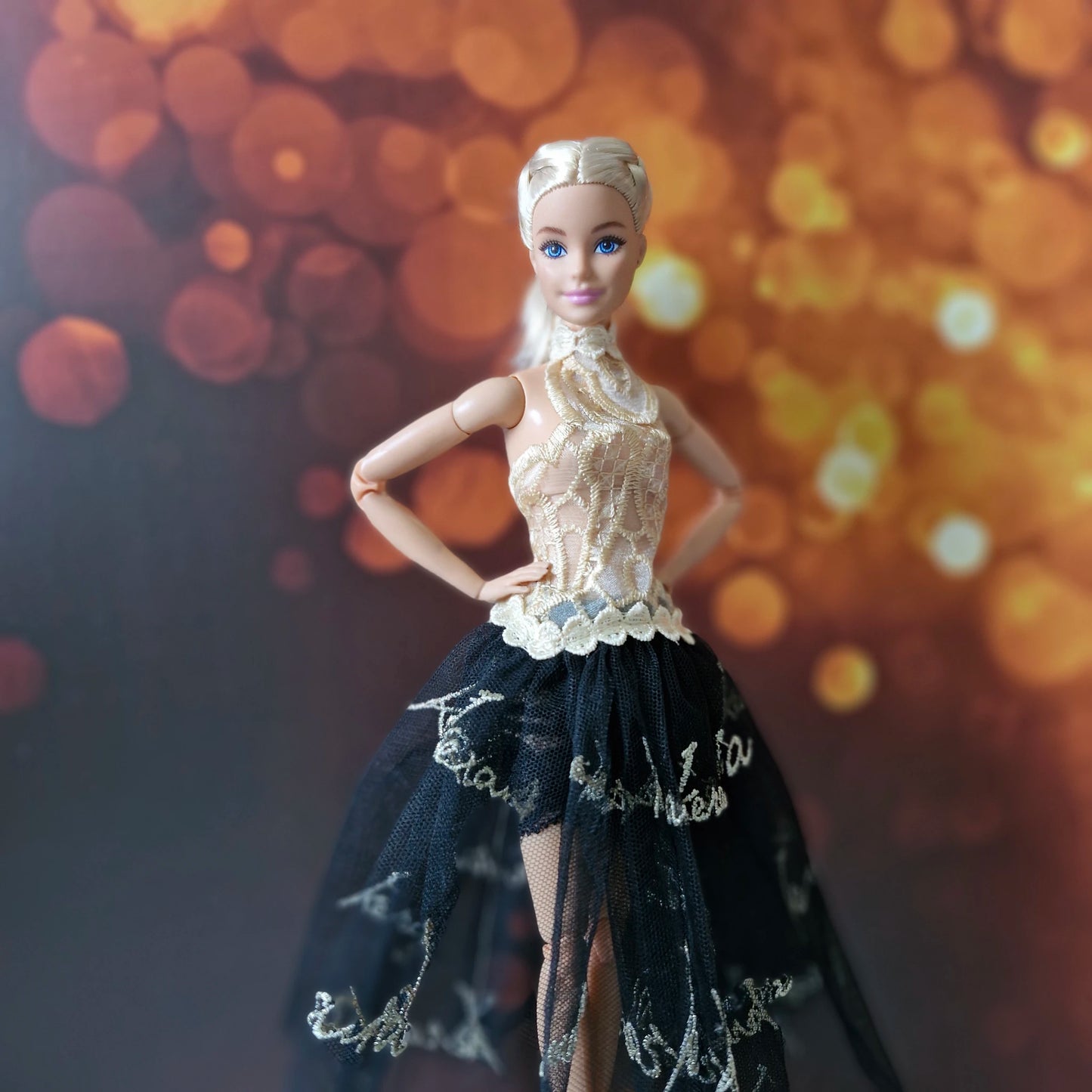 Close-up of blonde Barbie doll dressed in a detailed gold lace halter bodice and sheer black skirt