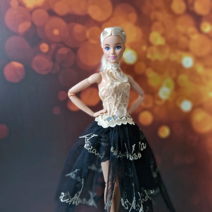 Close-up of blonde Barbie doll dressed in a detailed gold lace halter bodice and sheer black skirt