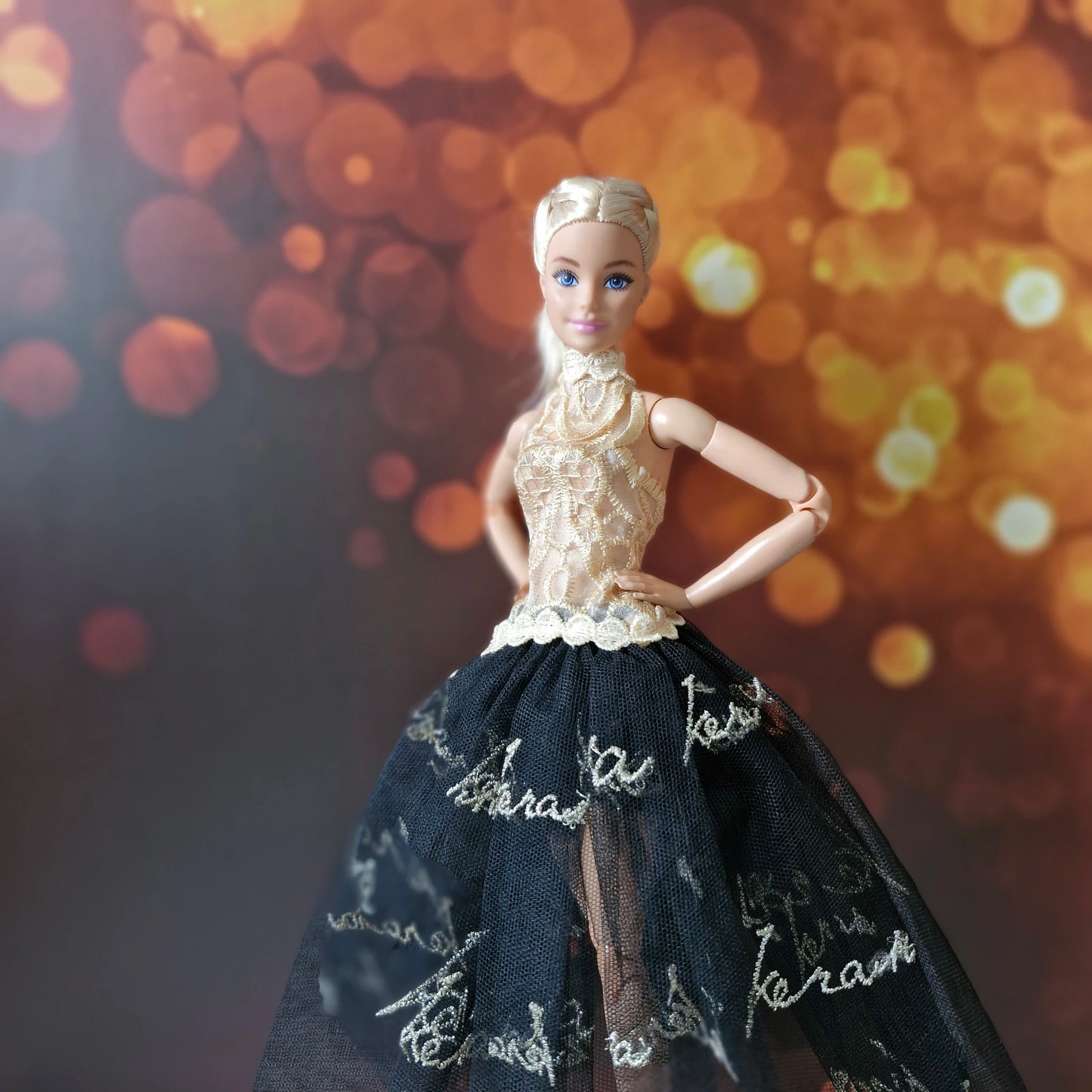 Glamorous Barbie doll outfit featuring a gold lace top and sheer black tulle skirt with gold writing